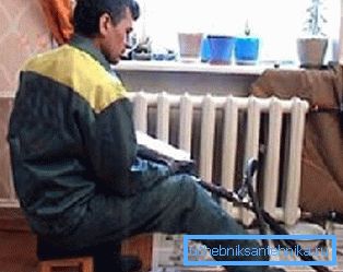Na fotografiji, vodovodar pere radiatorje v stanovanju Na fotografiji, vodovodar pere radiatorje v stanovanju