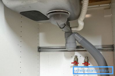 Pod kuhinjskim pomivalnim koritom.